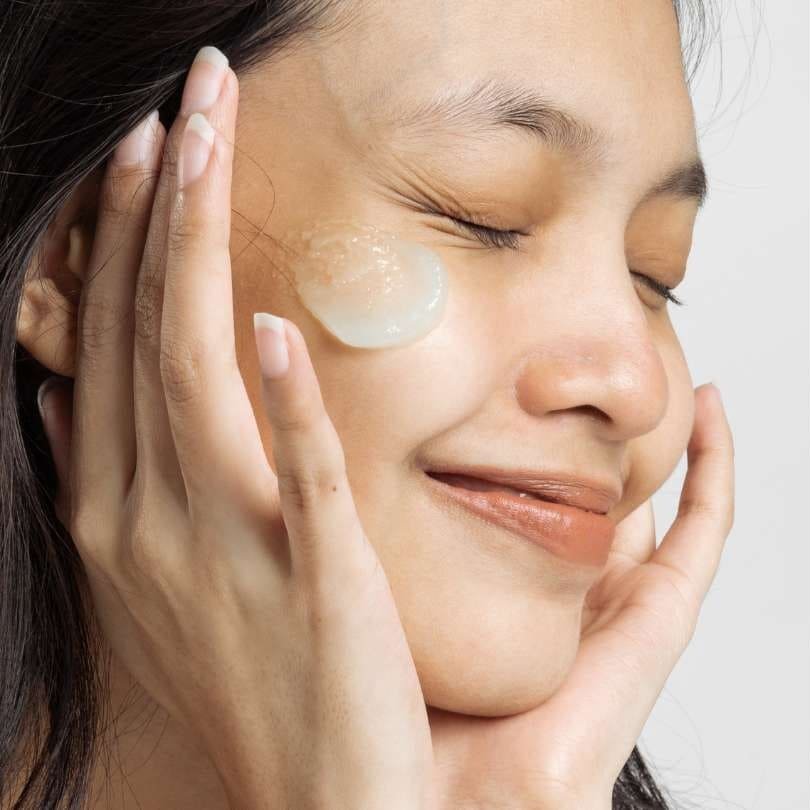 Woman applying skincare, symbolizing self-care and health as true beauty