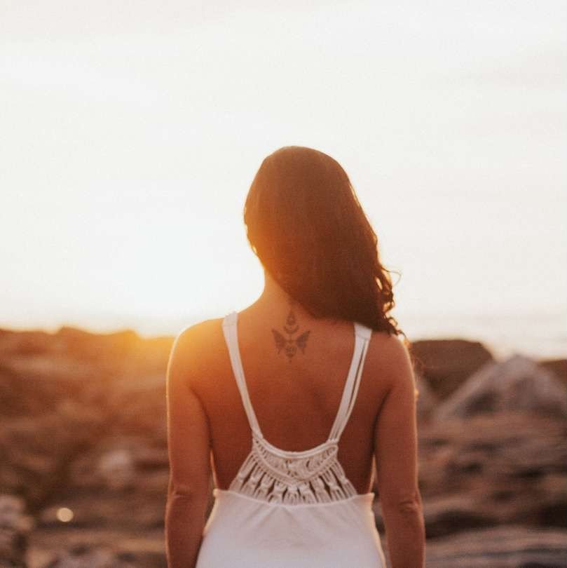 Woman with her back to the camera overlooking a beautiful landscape, symbolizing self-love and reflection
